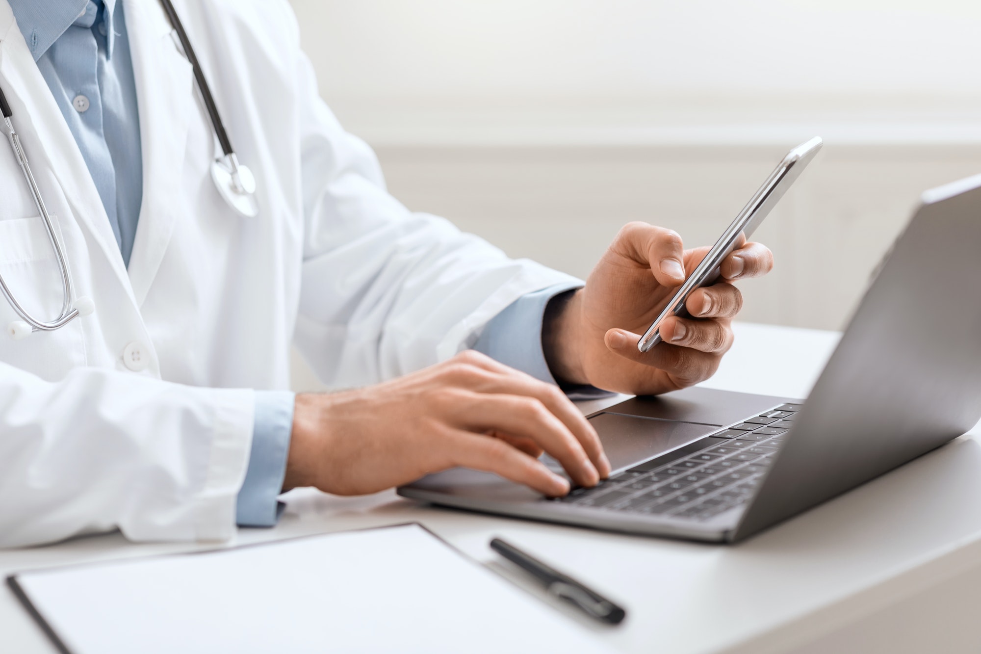 Doctor working with smartphone and laptop , close up